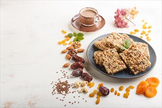 Homemade granola from oat flakes, dates, dried apricots, raisins, nuts in blue ceramic plate with a