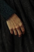 A close-up of a hand against dark fabric exudes a simple elegance