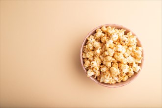 Popcorn with caramel in ceramic bowl on pastel orange background. Top view, flat lay, copy space