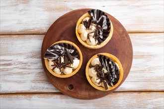 Sweet tartlets with chocolate and cheese cream on a white wooden background. top view, flat lay,