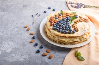 Homemade layered Napoleon cake with milk cream. Decorated with blueberry, almonds, walnuts,