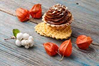 Sweet waffle, cake with cream and red physalis on a rustic blue wooden background