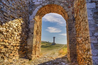 Stone arch with view of a path and ancient column in the background, sea fortress Methoni,