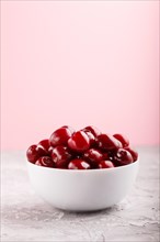 Fresh red sweet cherry in white bowl on gray and pink background. side view, close up, selective