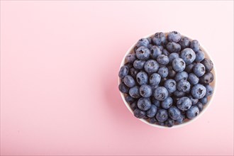 Fresh blueberry in white bowl on pink background. top view, copy space, flat lay