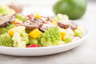 Vegetarian salad from romanesco cabbage, champignons, cranberry, avocado and pumpkin on a white