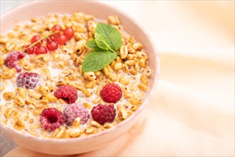 Wheat flakes porridge with milk, raspberry and currant in ceramic bowl on gray concrete background