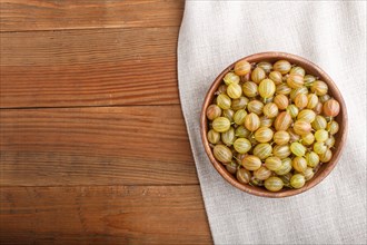 Fresh green gooseberry in wooden bowl on wooden background. top view, flat lay, copy space
