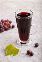 Glass of red grape juice on a gray concrete background. Morninig, spring, healthy drink concept.