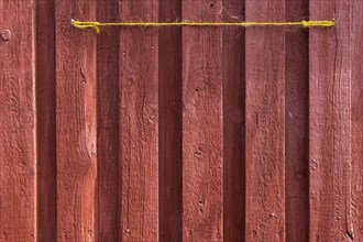 Red wooden wall of a fisherman's hut with yellow string, Hvide Sande, Midtjylland region, Denmark,