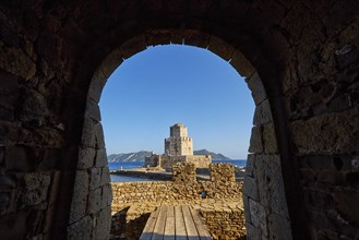 View through an arched entrance to a castle by the sea, octagonal medieval tower. Islet of Bourtzi,