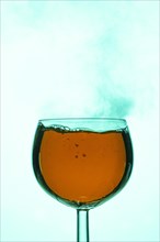 Smoky vapours rise through an orange liquid in a wine glass