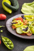 Vegetarian salad from green pea, tomatoes, pepper and basil on a black concrete background and