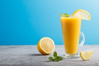 Glass of lemon drink on a gray and blue background. Morninig, spring, healthy drink concept. Side