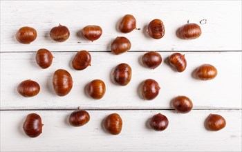 Pile of sweet chestnuts on white wooden background