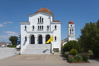 An imposing whitewashed church with a red roof and bell tower on a sunny day, Greek Orthodox Church