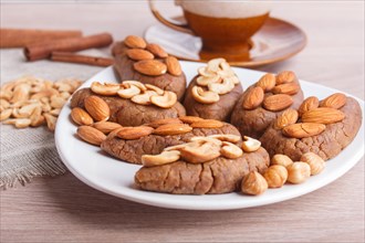 Small cakes potatoes with almonds and cashew nuts on a dessert plate. A cup of coffee, cinnamon,