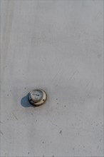 Thermometer mounted on outside wall of dirty white concrete wall. Temperature in photo incorrect in