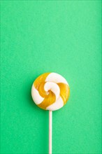Single lollipop candy on green pastel background. copy space, top view, flat lay