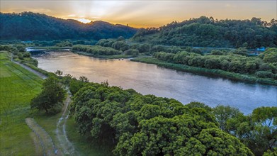 An aerial shot of a river winding through a lush landscape at sunset, in South Korea