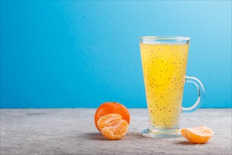 Glass of tangerine orange colored drink with basil seeds on a gray and blue background. Morninig,