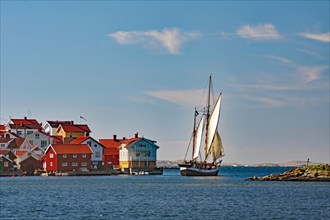 Sailing ship leaving a small harbour on the Swedish west coast, wooden houses, Kaeringon, Sweden,