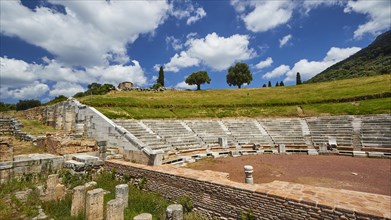 Historic theatre site with tiered rows of seats under a partly cloudy sky, Ancient Theatre,