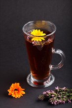 Glass of herbal tea with calendula and hyssop on a black background. Morninig, spring, healthy