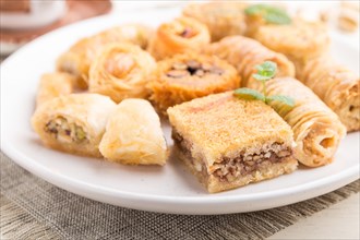Traditional arabic sweets (kunafa, baklava) and a cup of coffee on a white wooden background and