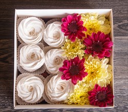 White box with white homemade zephyr and sunflowers and chrysanthemums on gray wooden background