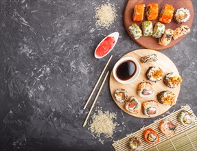 Different kinds of maki sushi rolls with salmon, sesame, cheese, roe and chopsticks, soy sauce,