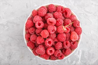 Fresh raspberry in white bowl on gray concrete background. top view, flat lay, close up