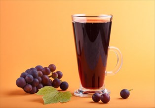 Glass of red grape juice on orange background. Morninig, spring, healthy drink concept. Side view,