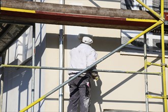 Painter painting the facade of a new residential building (Mutterstadt development area,