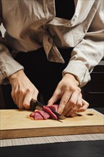 Close-up of woman's hands thinly slicing raw beef meat for Korean barbecue