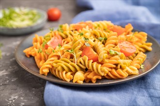Tortiglioni semolina pasta with tomato and microgreen sprouts on a black concrete background and