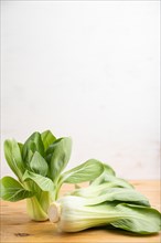 Fresh green bok choy or pac choi chinese cabbage on a brown wooden background. Side view, copy