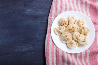 Dumplings on a linen tablecloth on a black wooden background. top view, flat lay, copy space
