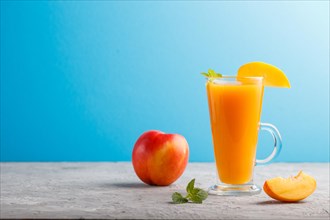 Glass of peach juice on a gray and blue background. Morninig, spring, healthy drink concept. Side