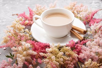 Pink and red astilbe flowers and a cup of coffee on a gray concrete background. Morninig, spring,