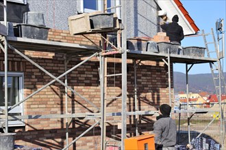Bricklaying, clinker brick work. Bricklayers clad the facade of a detached house with clinker