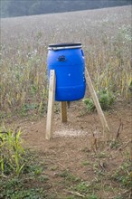 Blue barrel tripod bird feeder in field, Ramsholt, Suffolk, England, United Kingdom, Europe