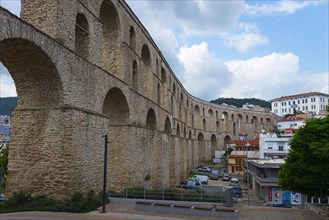 A Roman aqueduct spans a modern cityscape under a cloudy sky, Kavala, Dimos Kavalas, Eastern