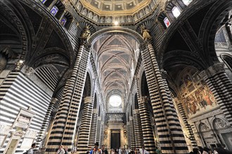 The nave of the cathedral with its black and white striped marble columns, cross and round arches,