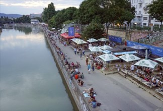 People relaxing in summer temperatures on the banks of the Danube Canal in Vienna, 19 July 2019