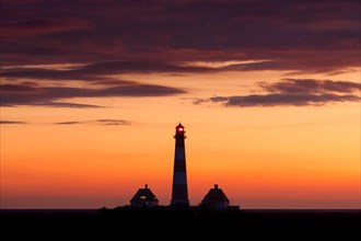 Lighthouse Westerheversand silhouetted against orange sunset sky, Westerhever, Wadden Sea National