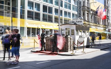A long exposure shows a tourist at Checkpoint Charlie, men in American military uniforms stand in