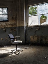 Single swivel chair, office chair in an empty dilapidated factory building, peeling paint,