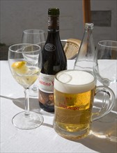 Beer and iced water glasses and wine bottle on restaurant table in Spain