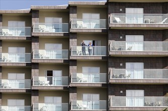 An elderly couple looks out from a balcony of an apartment complex in Torremolinos, Costa del Sol,